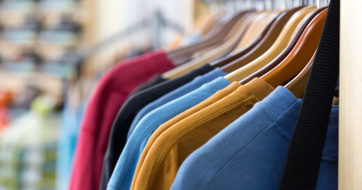 A rack of folded apparel in assorted colours ready for decoration